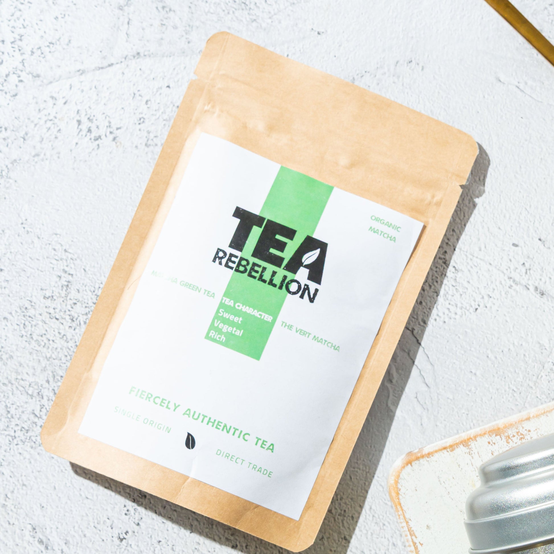 Tea Rebellion matcha product on a light gray surface with a spoon.